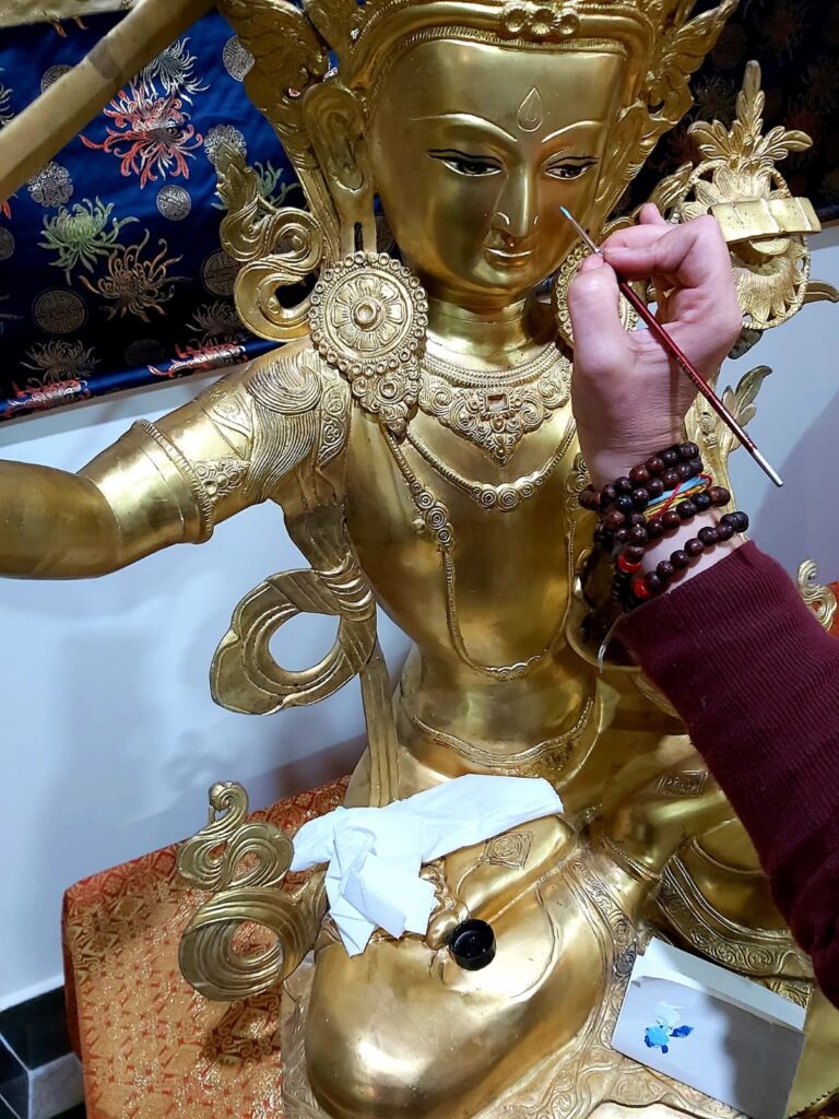 Buddhista szobor részlete festés közben, málával